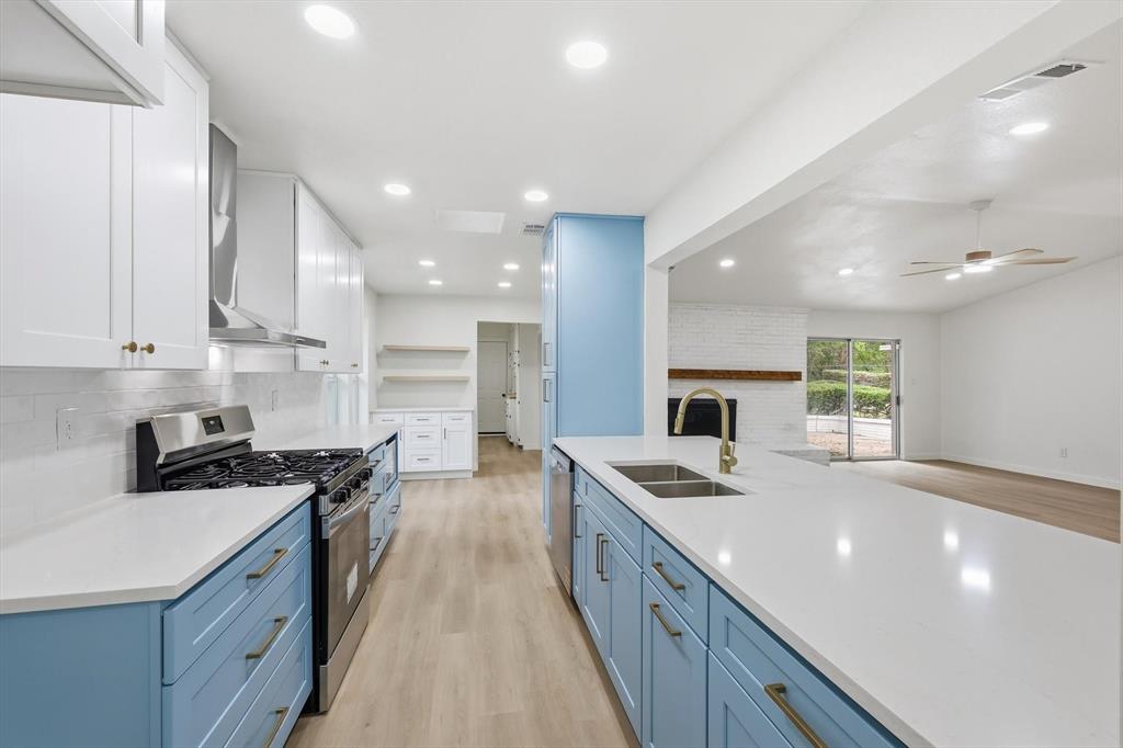 5940 Hunters View Lane Dallas, TX 75232 - Photo 4 of 24 Kitchen featuring blue cabinetry, light wood-style flooring, appliances with stainless steel finishes, white cabinetry, and recessed lighting