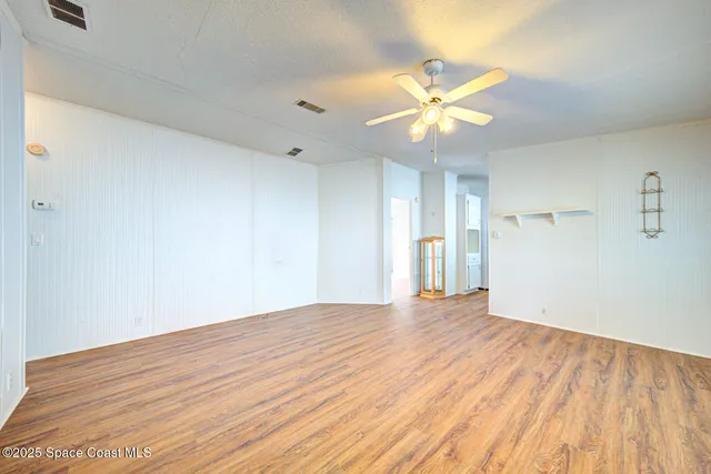 a view of an empty room with window and wooden floor