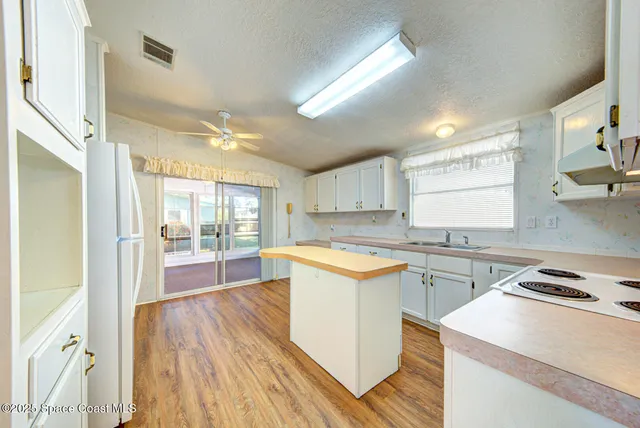 a kitchen with a sink a stove cabinets and wooden floor