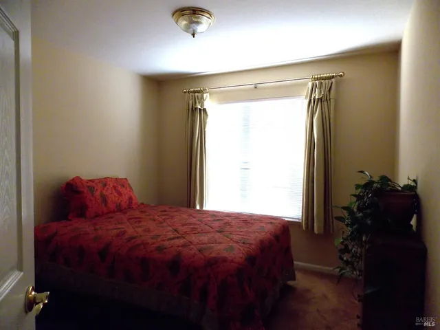 a bed sitting in a bedroom next to a window and a wooden floor