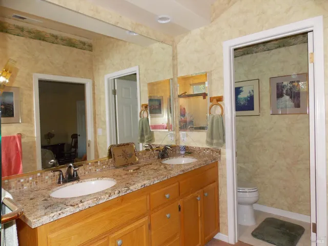 a bathroom with a granite countertop sink toilet a mirror and shower