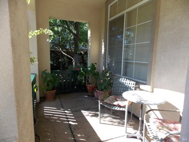 a backyard of a house with table and chairs potted plants
