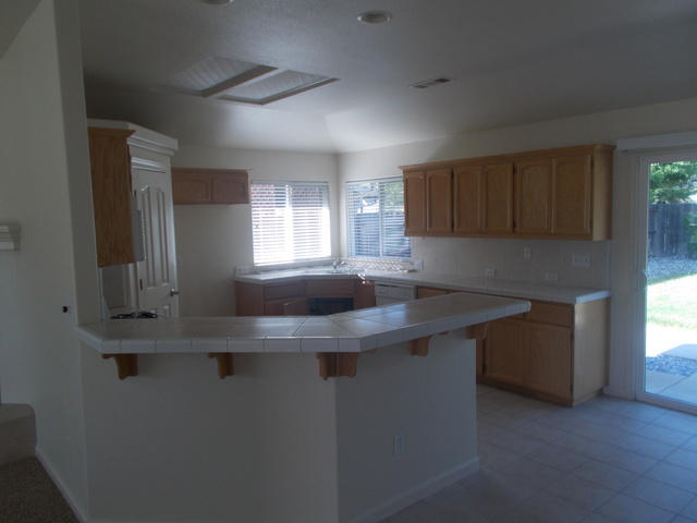 2649 Rhinestone Way Redding, CA 96001 - Photo 8 of 25 a kitchen with kitchen island granite countertop a sink window and cabinets