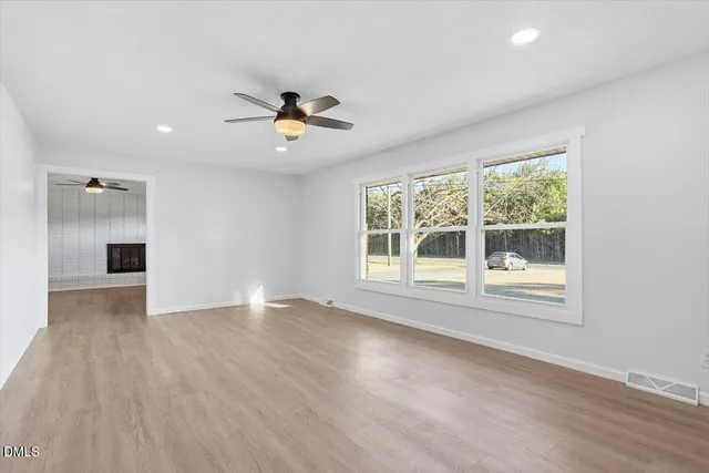 a view of an empty room with a window and wooden floor