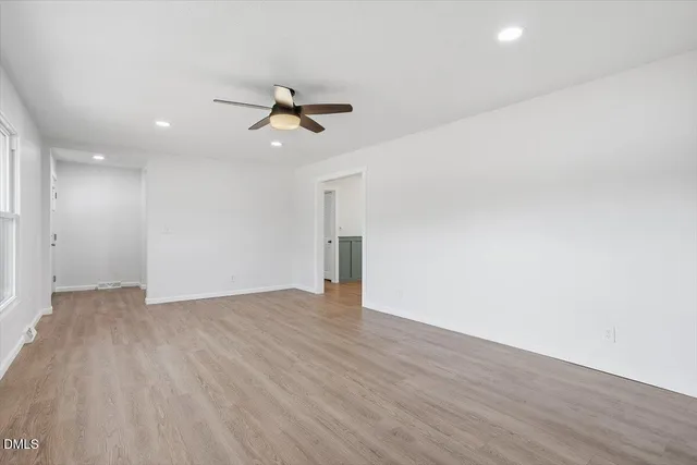 a view of empty room with wooden floor and ceiling fan