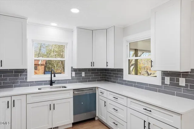 a kitchen with granite countertop white cabinets sink and window