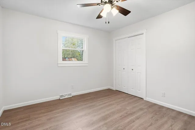a view of an empty room with wooden floor and a window