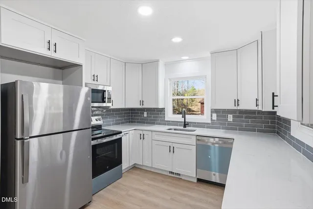 an empty room with windows and fireplace