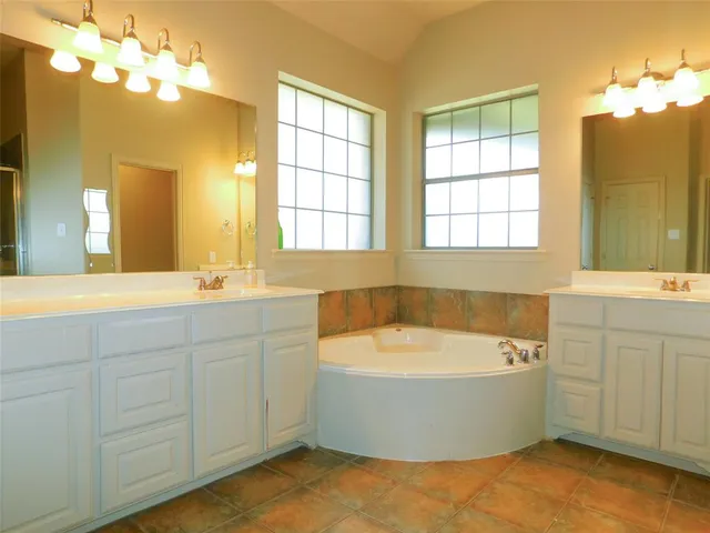 a bathroom with a bathtub a sink a mirror and a window