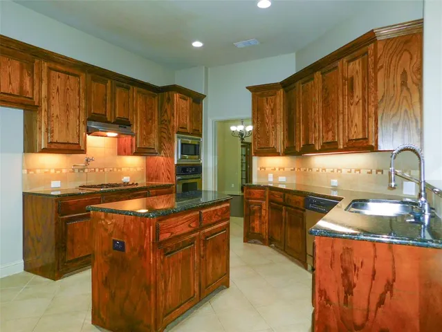 a kitchen with stainless steel appliances granite countertop wooden cabinets a sink and a stove
