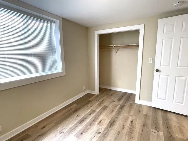 a view of an empty room with wooden floor and a window