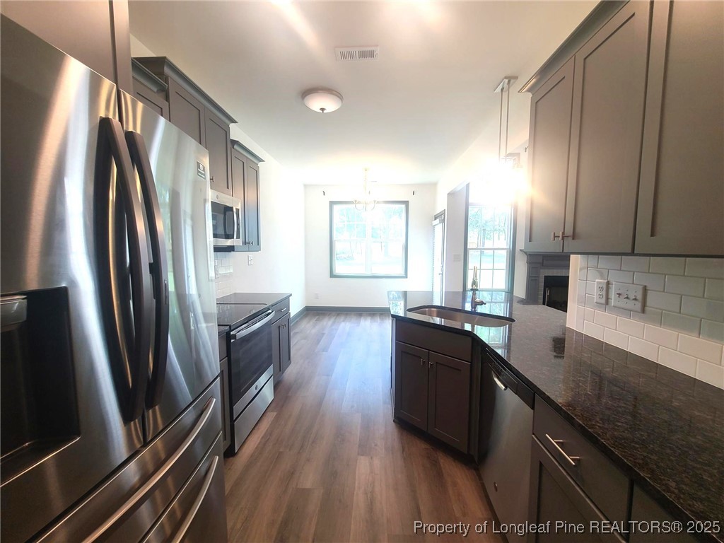 519 Hammond Farms Road Hope Mills, NC 28348 - Photo 15 of 34 a kitchen with stainless steel appliances granite countertop a refrigerator a sink dishwasher a stove and white countertops with wooden floor