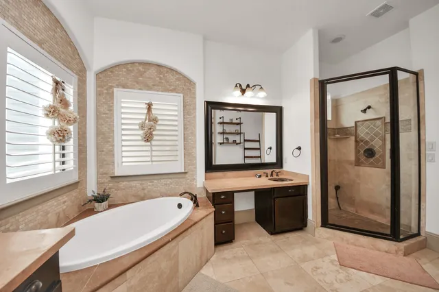 a bathroom with a granite countertop tub sink and mirror