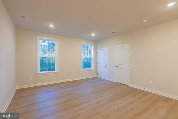 a view of an empty room with wooden floor and window