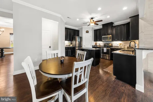 a kitchen with stainless steel appliances granite countertop a stove refrigerator and a dining table with wooden floor