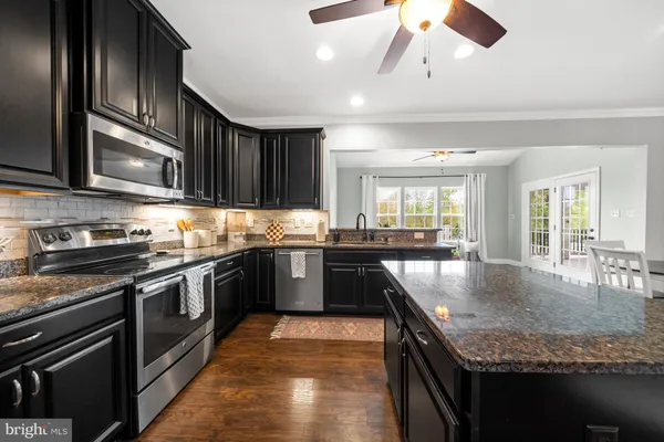 a kitchen with granite countertop a sink cabinets and stainless steel appliances