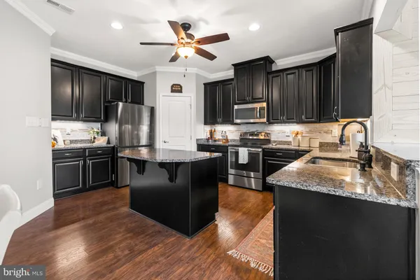 a kitchen with a dining table chairs stainless steel appliances and cabinets