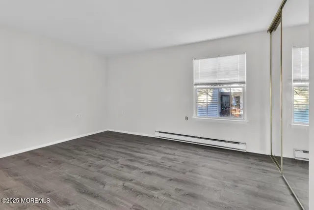 an empty room with wooden floor closet and windows