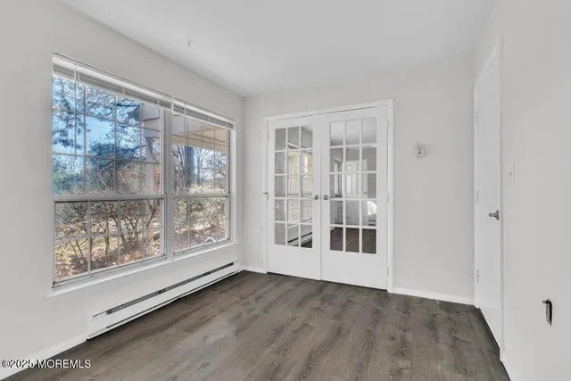 a view of an empty room with wooden floor and a window
