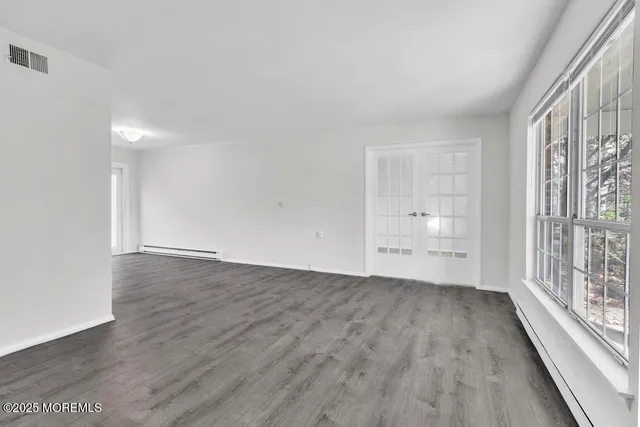 a view of an empty room with a window and wooden floor