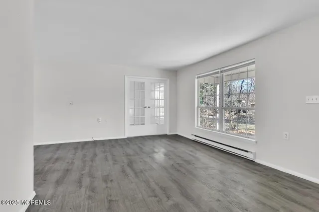 a view of an empty room with window and wooden floor