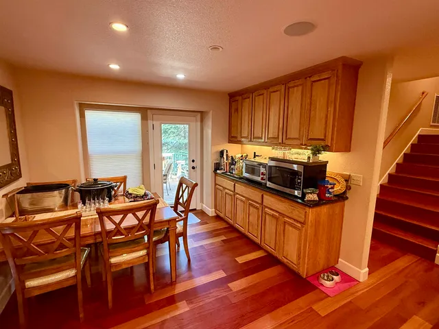 a kitchen with stainless steel appliances wooden floors wooden cabinets dining table and chairs