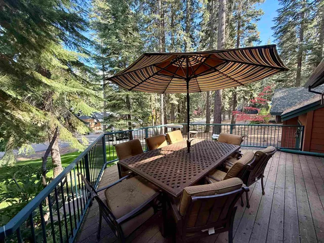 a view of a patio with table and chairs under an umbrella with wooden floor