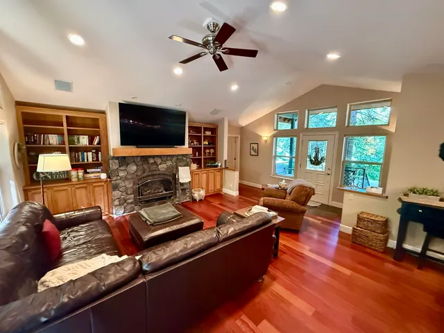 a living room with furniture floor to ceiling window hardwood floor and a flat screen tv