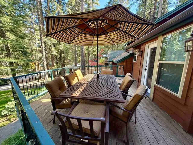 a patio with wooden floor a yard a table and chairs