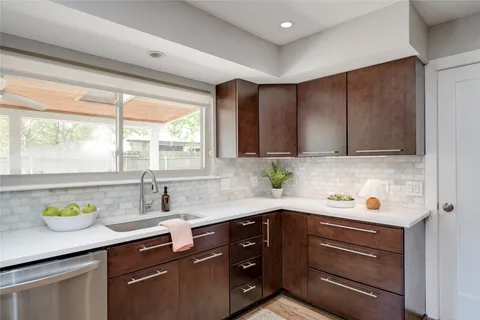 a kitchen with stainless steel appliances a sink a stove cabinets and a window