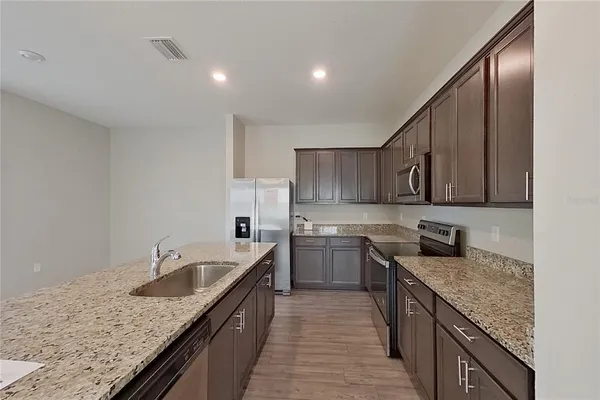 a kitchen with granite countertop a sink and dishwasher with wooden floor