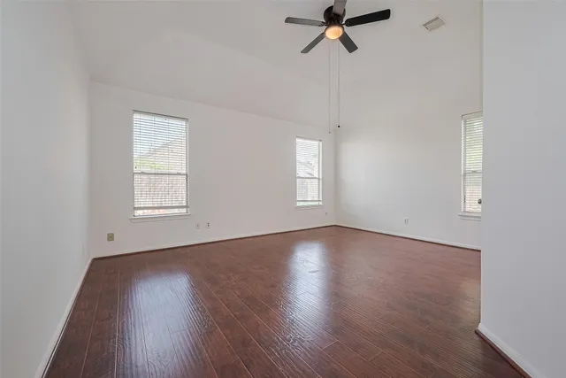 a view of an empty room with a window and wooden floor