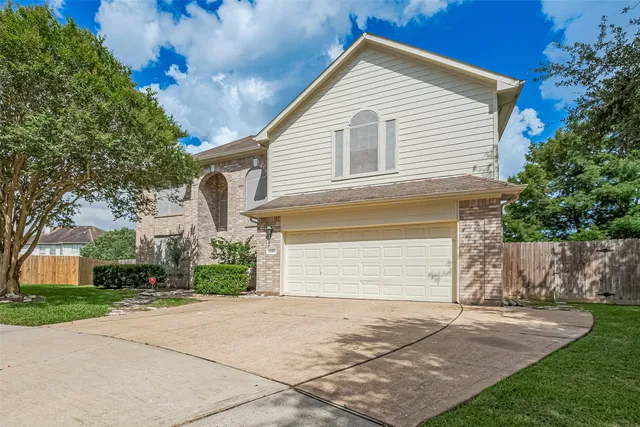 front view of house with a yard and an trees