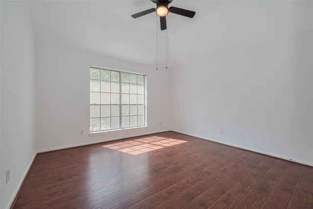 an empty room with wooden floor cabinet and windows