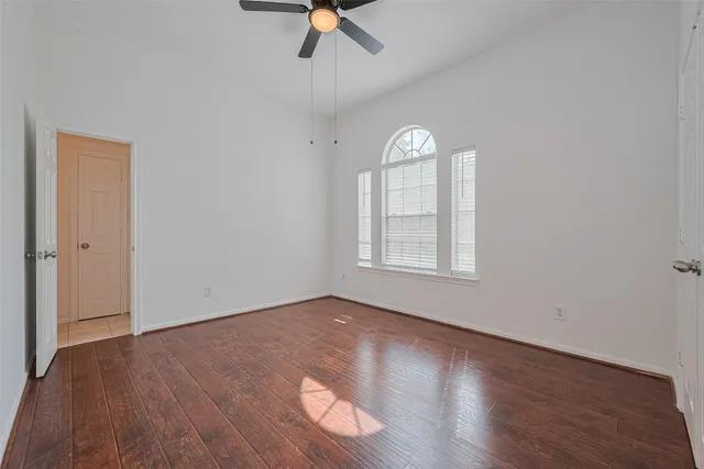 a view of an empty room with window ceiling fan and wooden floor