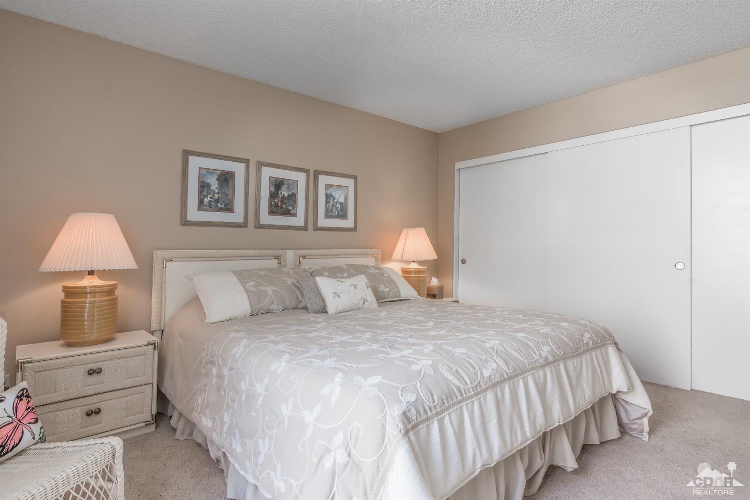72475 Rodeo Way, Unit 320 Rancho Mirage, CA 92270 - Photo 16 of 26 a bedroom with a bed and a lamp on the dresser