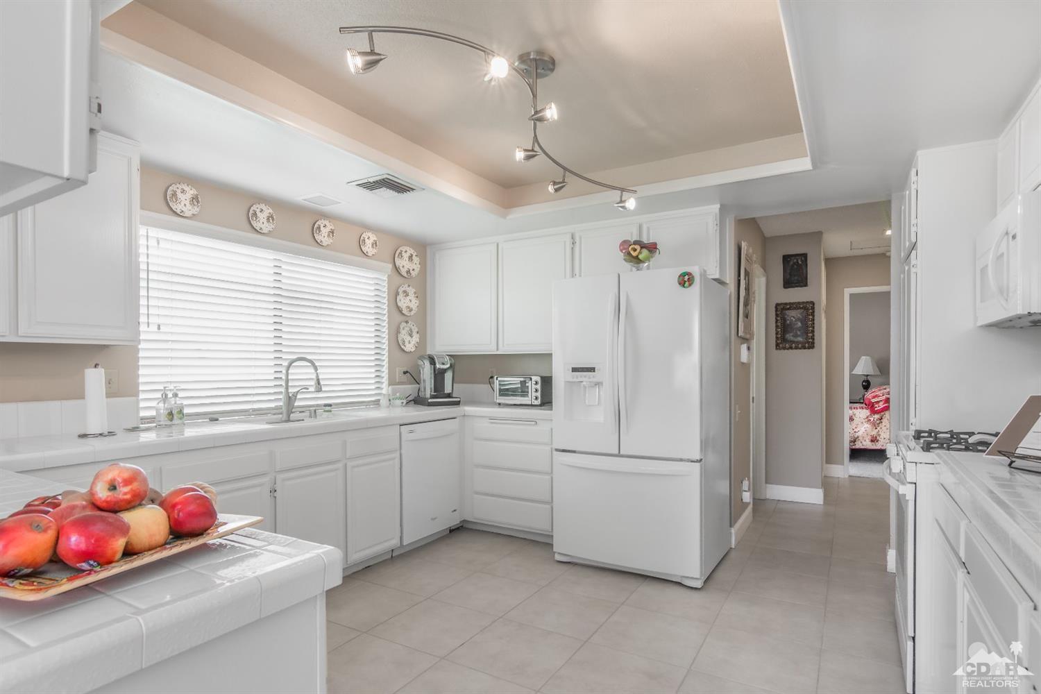 72475 Rodeo Way, Unit 320 Rancho Mirage, CA 92270 - Photo 3 of 26 a kitchen with white cabinets and refrigerator