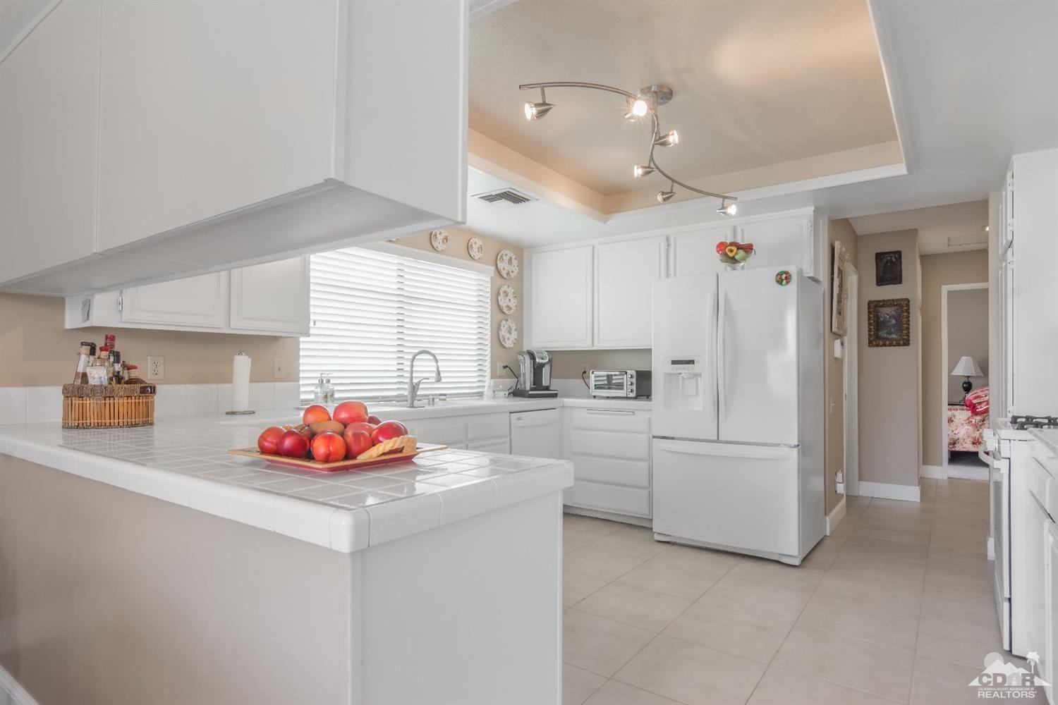 72475 Rodeo Way, Unit 320 Rancho Mirage, CA 92270 - Photo 5 of 26 a kitchen with white cabinets and refrigerator