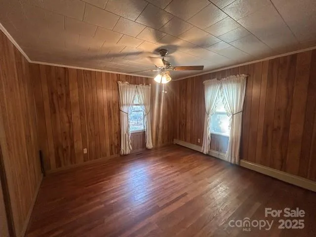 an empty room with wooden floor windows and entrance