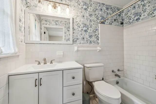 a bathroom with a toilet sink vanity and mirror