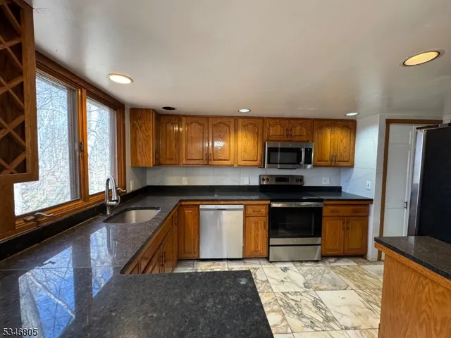 a kitchen with stainless steel appliances granite countertop a stove a sink and a microwave