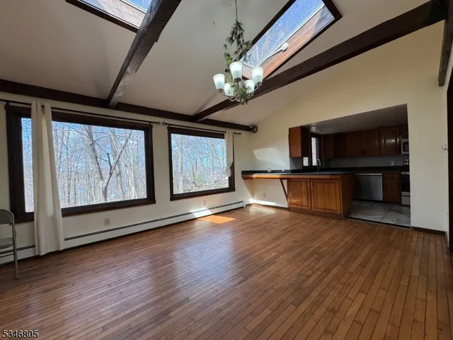 a view of an empty room with wooden floor fireplace and a window