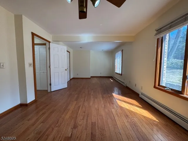 a view of an empty room with window and wooden floor