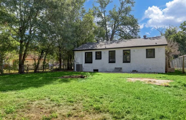 a backyard of a house with plants and large tree