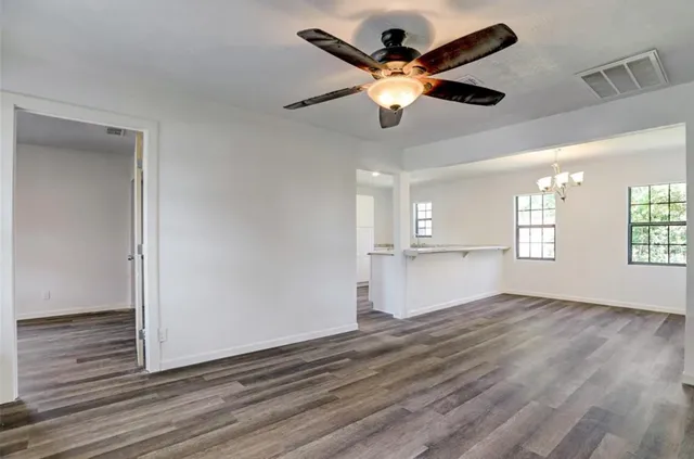 a view of an empty room with window and wooden floor