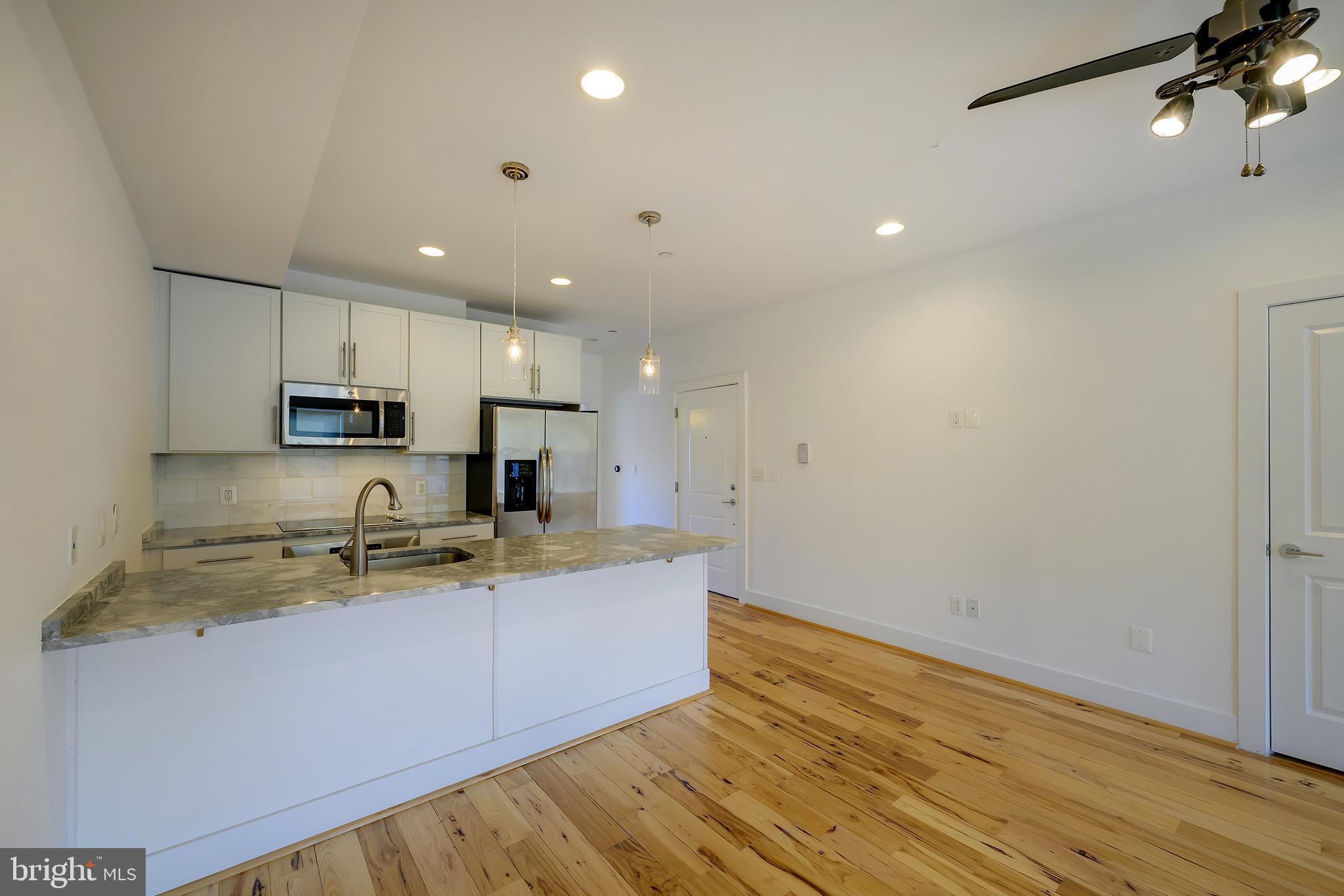 3325 11th Street Northwest, Unit 5 Washington, DC 20010 - Photo 8 of 25 a kitchen with stainless steel appliances granite countertop a sink refrigerator and microwave