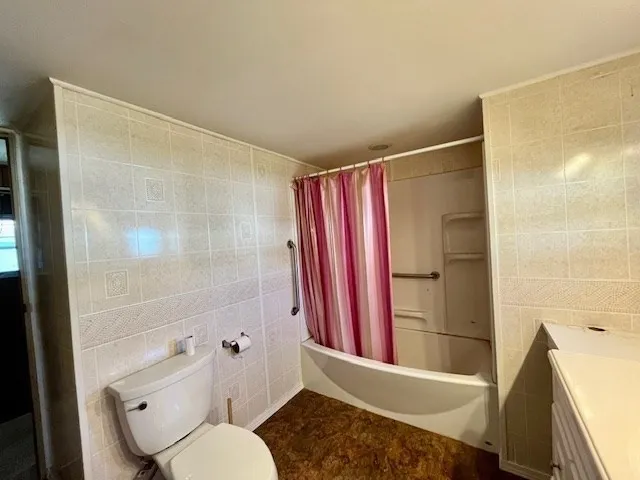 a bathroom with a granite countertop bathtub shower and toilet