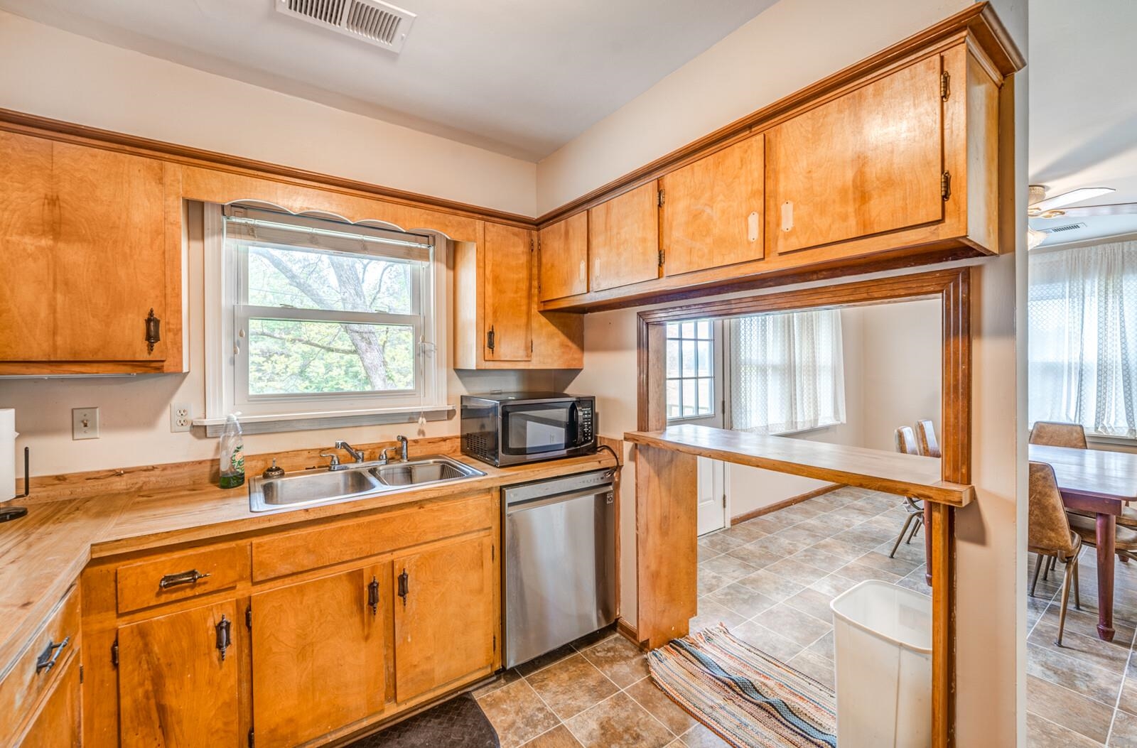 6125 Warren Road Oakland, TN 38060 - Photo 19 of 40 Kitchen featuring wood cabinetry, a double basin stainless steel sink, a stainless steel dishwasher, and a pass-through window with a breakfast bar