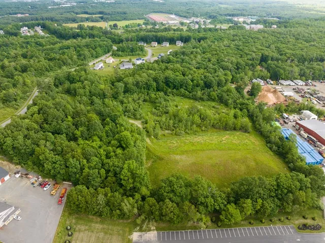 an aerial view of residential houses with outdoor space and trees