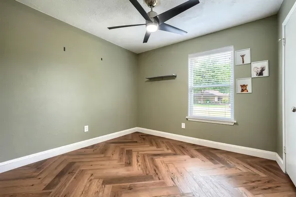 a view of empty room with wooden floor and fan